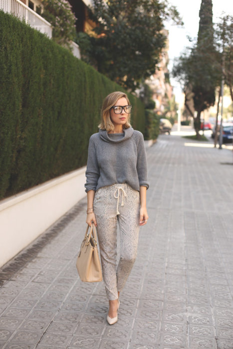 Chica usando pants de color beige con un abrigo de color gris y zapatos de tacón 