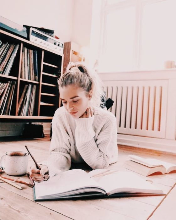 Chica estudiando dentro de su recamara