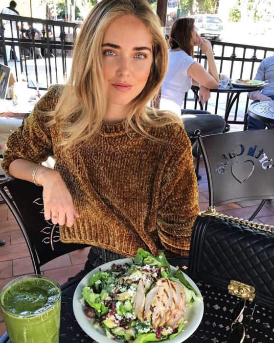 Chica en un restaurante comiendo ensalada de pollo 
