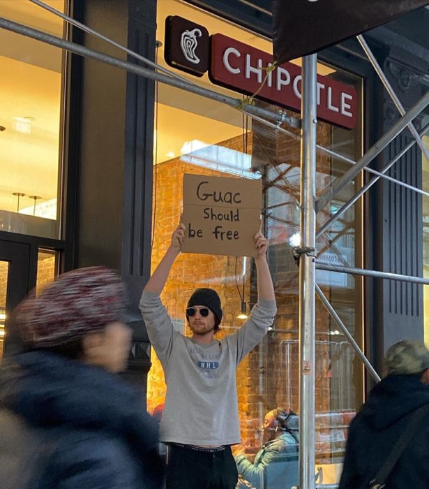 Chico con una pancarta protestando por que el guacamole debería ser gratis 