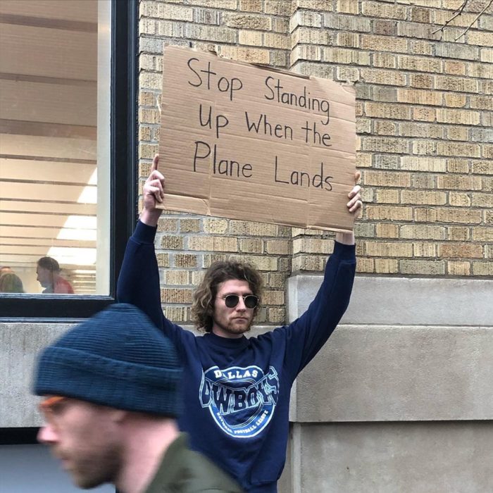 Chico con una pancarta protestando por la gente que se para en los aviones 