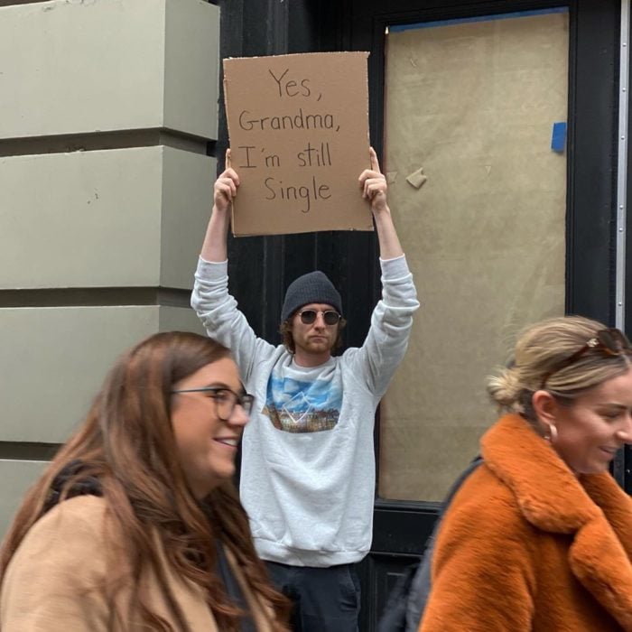 Chico con una pancarta protestando sobre su soltería 