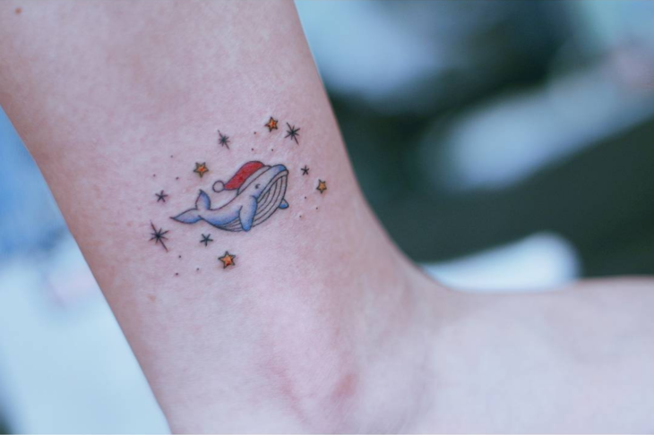 Tatuaje de una ballena con gorro navideño 