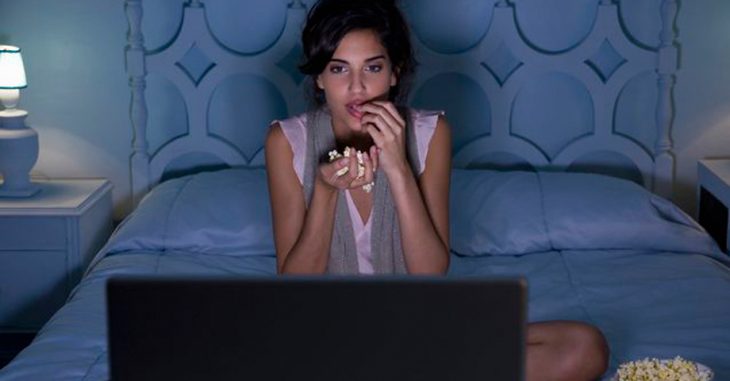 Chica comiendo palomitas y viendo la televisión