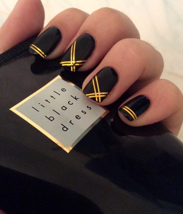 Manicure negro con líneas doradas para la fiesta de Año Nuevo; uñas largas y cuadradas