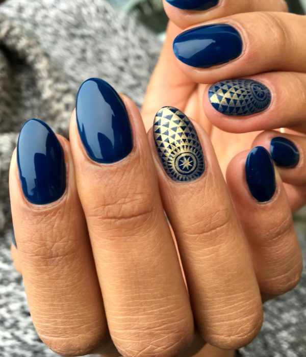 Manicure azul con figuras doradas para la fiesta de Año Nuevo; uñas largas en forma de almendra