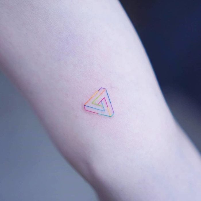 Tatuaje pequeño triángulo en líneas de colores en el brazo
