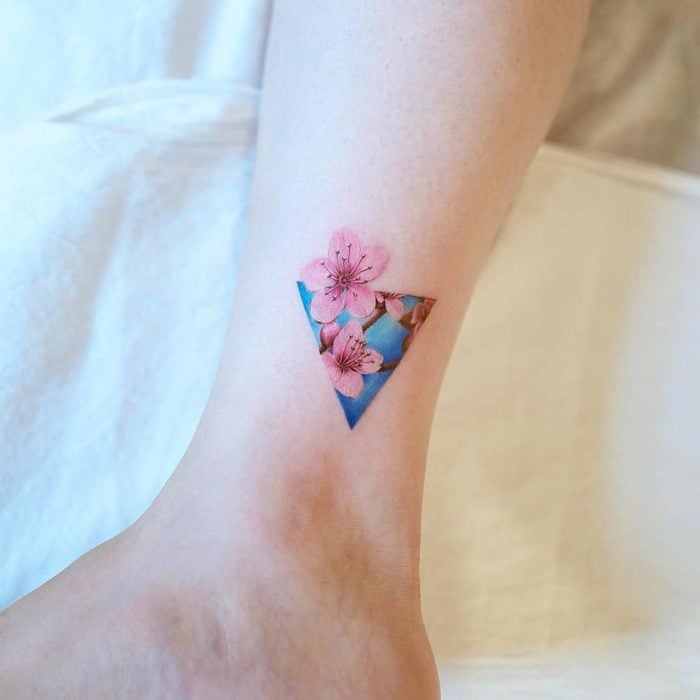 Tatuaje pequeño tobillo triángulo y flores de almendro rosa