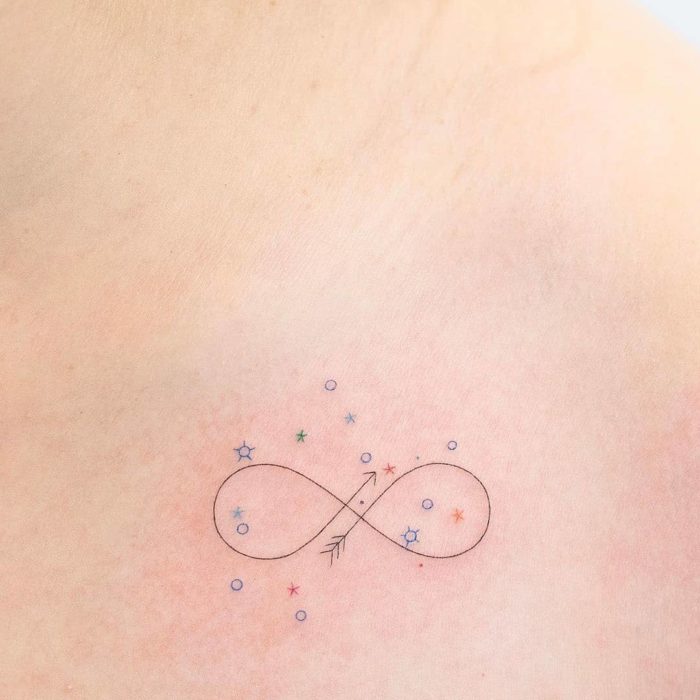 Tatuaje pequeño símbolo infinito y estrellas de colores