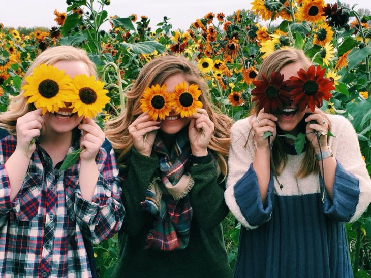 Amigas con flores en el rostro y felices