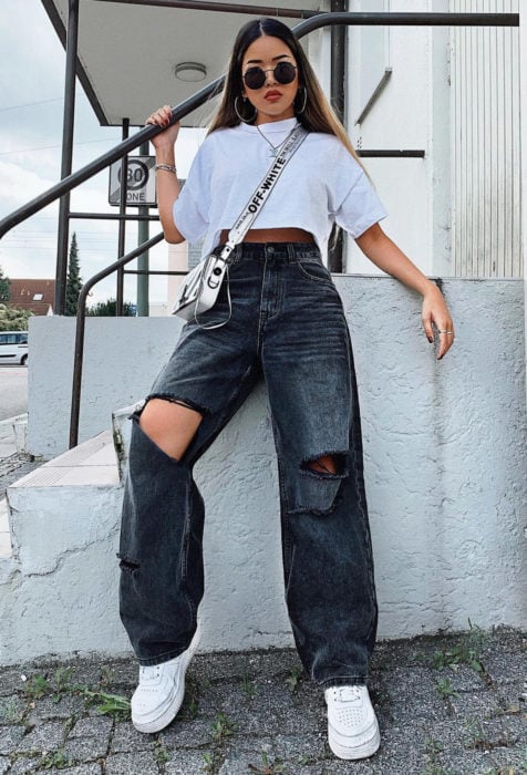 Looks con baggy jeans; chica de cabello largo y lacio con estilo street style, crop top blanco, pantalones oversized y lentes redondos