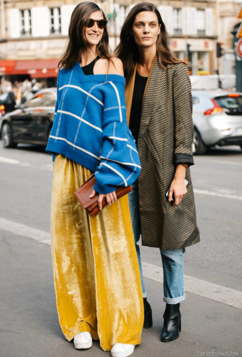 Looks con baggy jeans; amigas en la calle con suéter oversized azul, pantalón holgado amarillo de gamuza, saco largo café