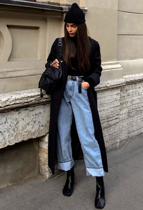 Looks con baggy jeans; chica con gorro, abrigo negro, botines y pantalón de mezclilla oversized 