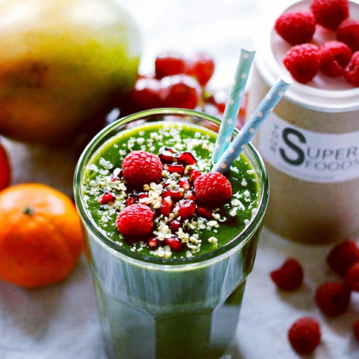 Jugo verde con frutos rojos en vaso de cristal