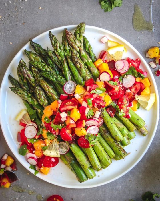 Plato de comida alcalina, esparragos con rabanos, y verduras varias, además de aceite de oliva