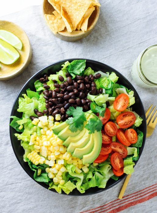 Plato de comida, ensalada con legumbres, limón, y algunos totopos