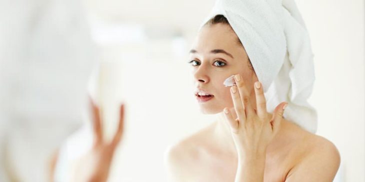 Chica hidratando su piel con crema humectante después de tomar un baño