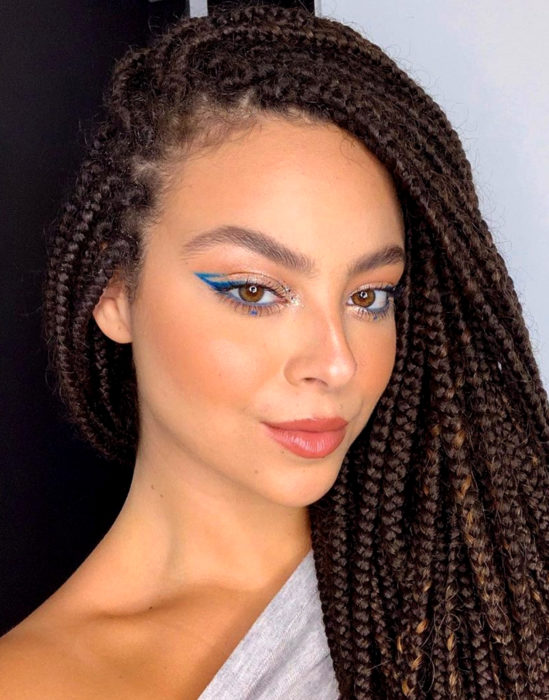 Maquillaje tendencia para el 2020;; delineado gráfico o flotante color azul; mujer afroamericana con trenzas 