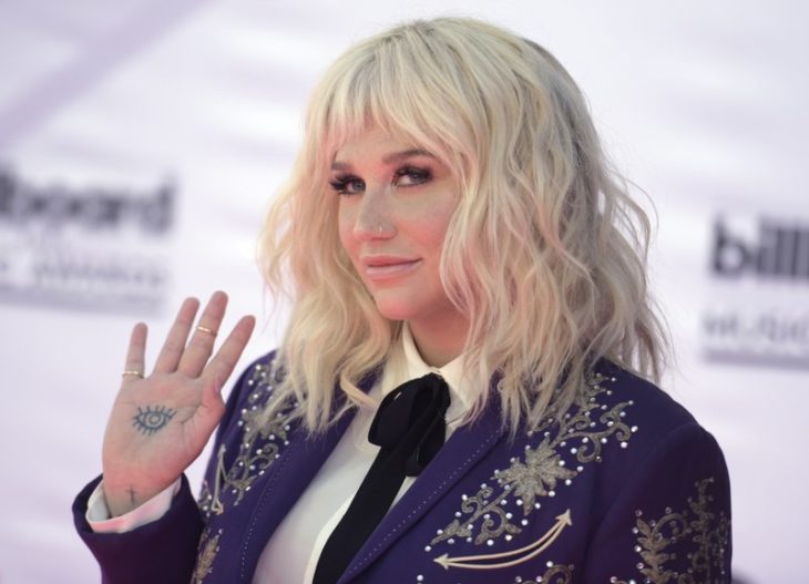 Kesha mostrando un tatuaje en la palma de su mano en una alfombra roja