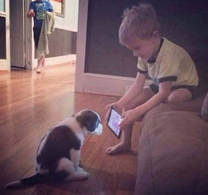 Niño enseñándole tablet a un perrito