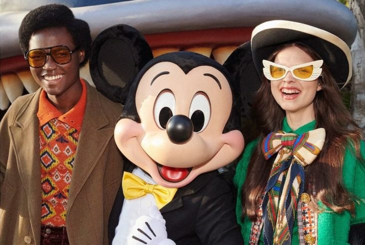 Pareja sonriendo y modelando para la colección Gucci x Mickey Mouse