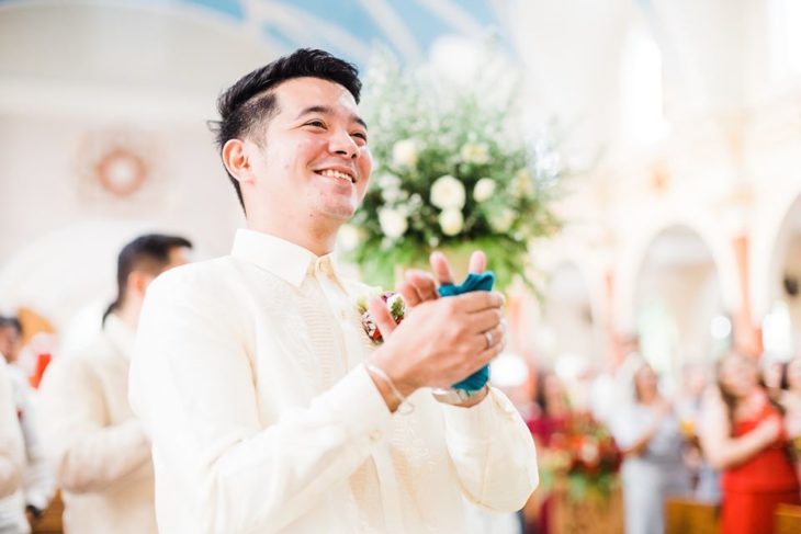 Chico vestido de novio mientras ve a su esposa caminando hacia el altar 