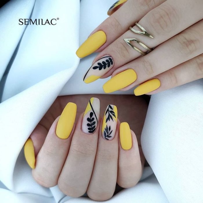 Manicura amarilla con diseño de flores en negro y efecto mate