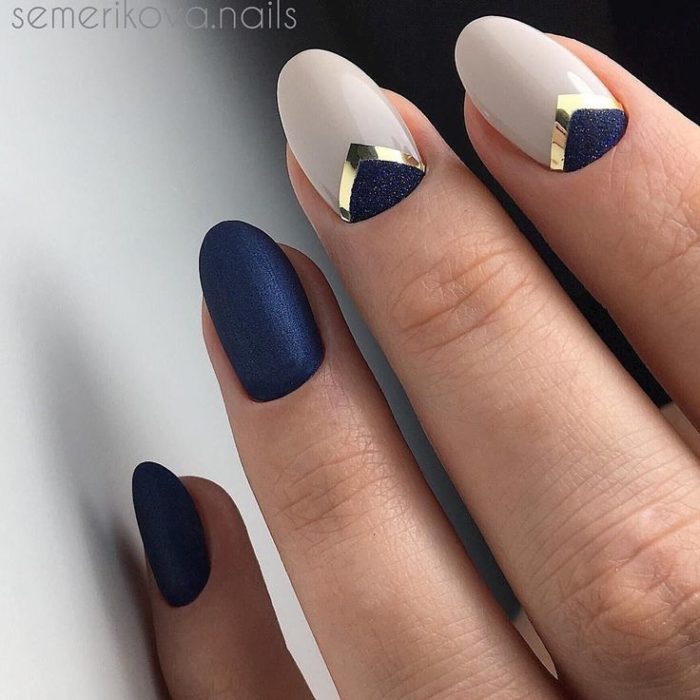 Manicura en tono azul marino y beige con detalles dorados