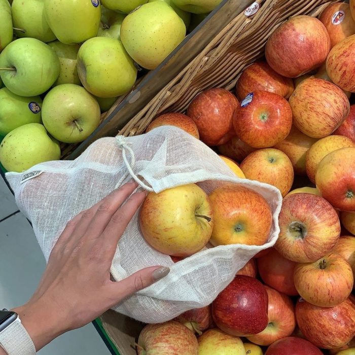 Mano escogiendo manzanas rojas y verdes en canastas de mimbre