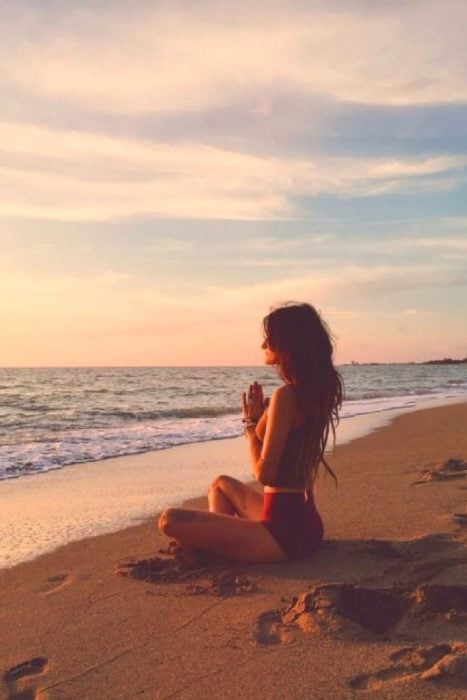 Mujer haciendo meditación en la playa