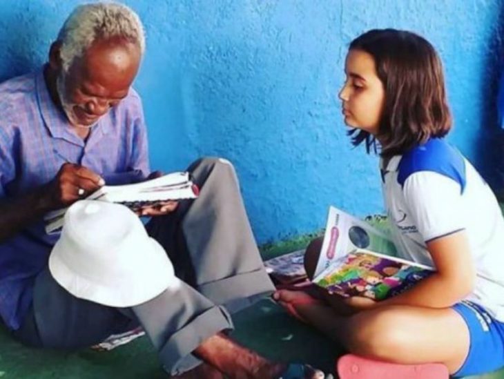 Bárbara Matos y Francisco Santana Filho leyendo, niña y señor de los helados sentado en la acera de la avenida