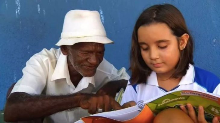 Bárbara Matos y Francisco Santana Filho leyendo, niña y señor de los helados sentado en la acera de la avenida