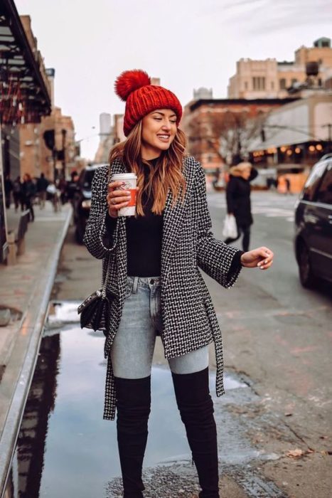 Chica llevando botas altas con skiny jeans y suéter a cuadros