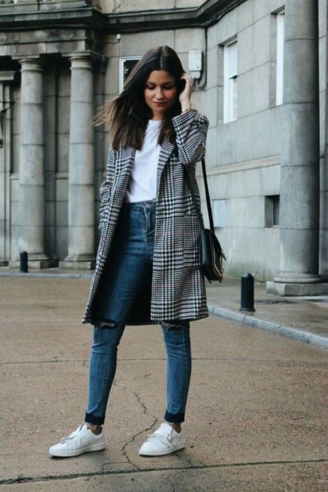 Chica con un saco, jeans y tenis de color blanco 