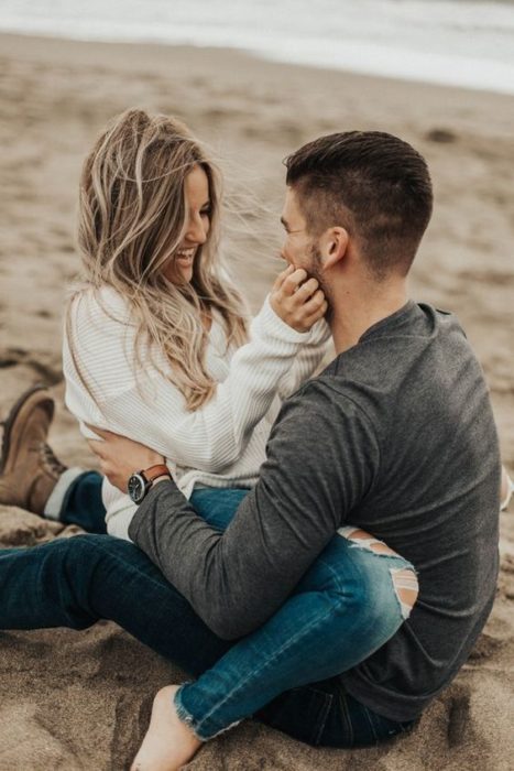 Pareja sentados en la playa riendo