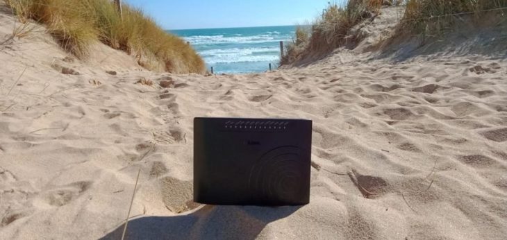 Módem de internet colocado en la arena mientras mira el mar 