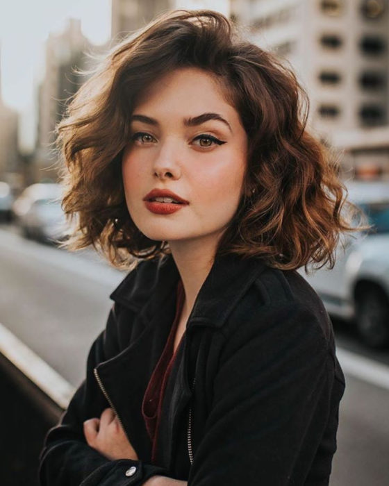 Peinados para San Valentín; mujer posando para foto en la calle, con cabello bob corto, ondulado y suelto