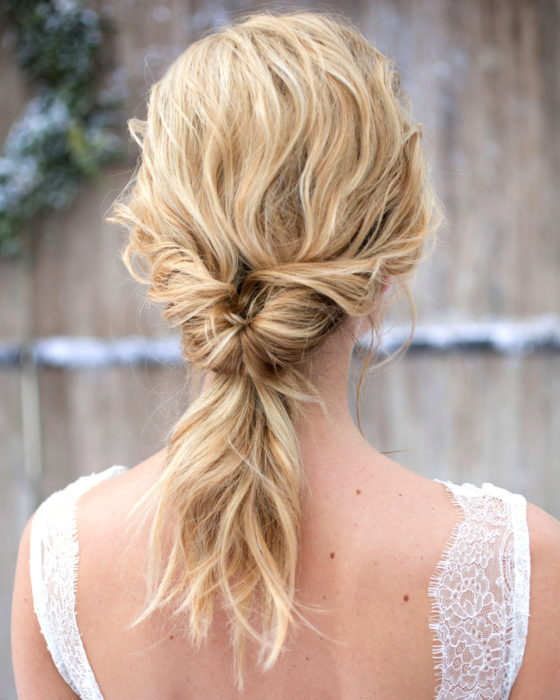 Peinados para San Valentín; mujer de cabello rubio, ondulado, peinado de cola baja con twist