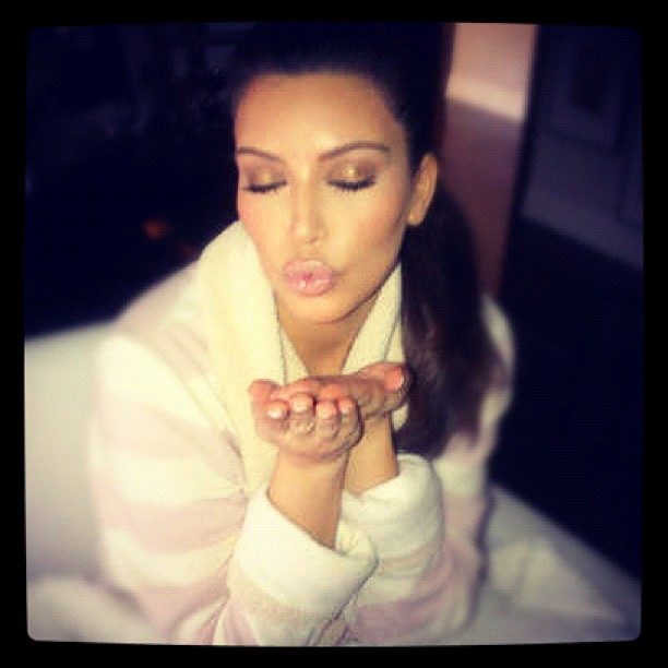 Kim Kardashian sentada en su cama aventando un beso 