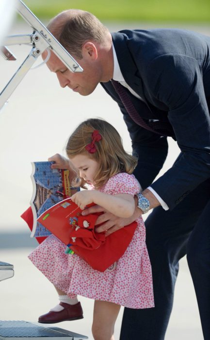 Principe William ayudando a subir los escalones del avión a la princesa Carlota