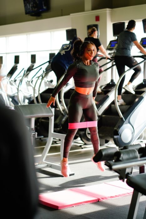 Chica haciendo sentadilla con salto en gimnasio, sobre tapete