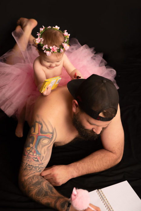 Padre e hija con tutu recostados en n el suelo coloreando un libro