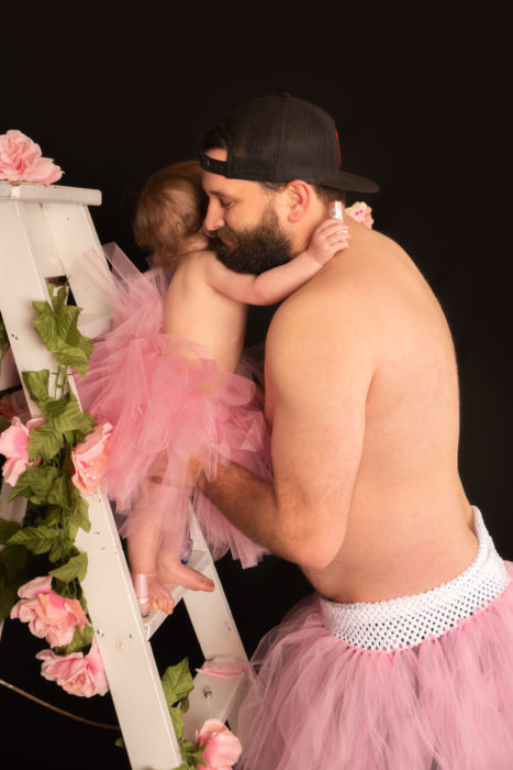 Padre e hija usando tutus, abrazados sobre una escalera