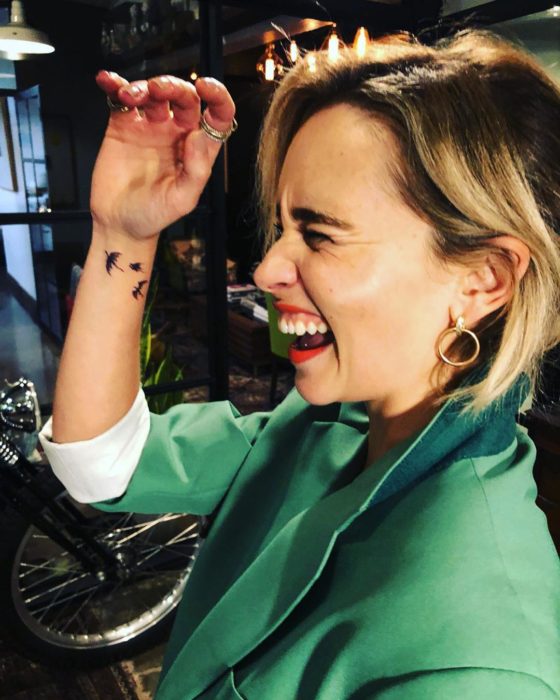 Emilia Clarke con saco demostrando su tatuaje de dragones