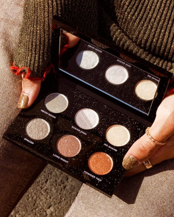 Manos sosteniendo paleta de sombras metalizadas con packaing negro