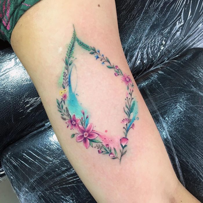 Tatuaje óvalo de flores de colores fríos