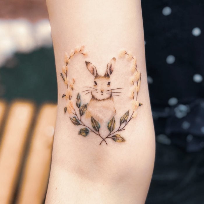 Tatuaje conejo en tonos pastel con flores formando corazón