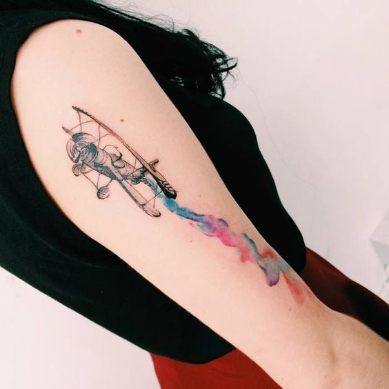 Chica con tatuaje de avioneta con estela de colores