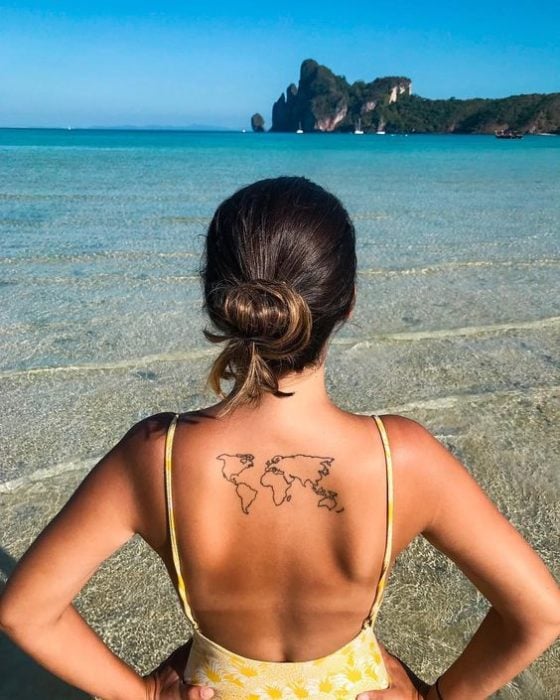 Chica con tatuaje en la espalda de mapamundi en silueta negra