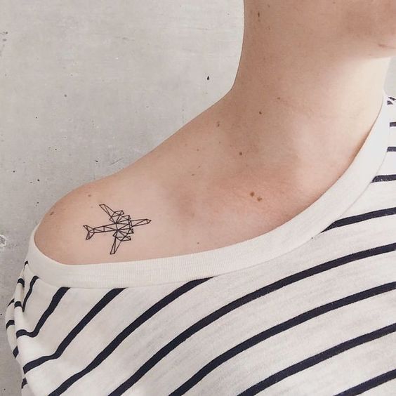 Chica con tatuaje de avión minimalista en el hombro